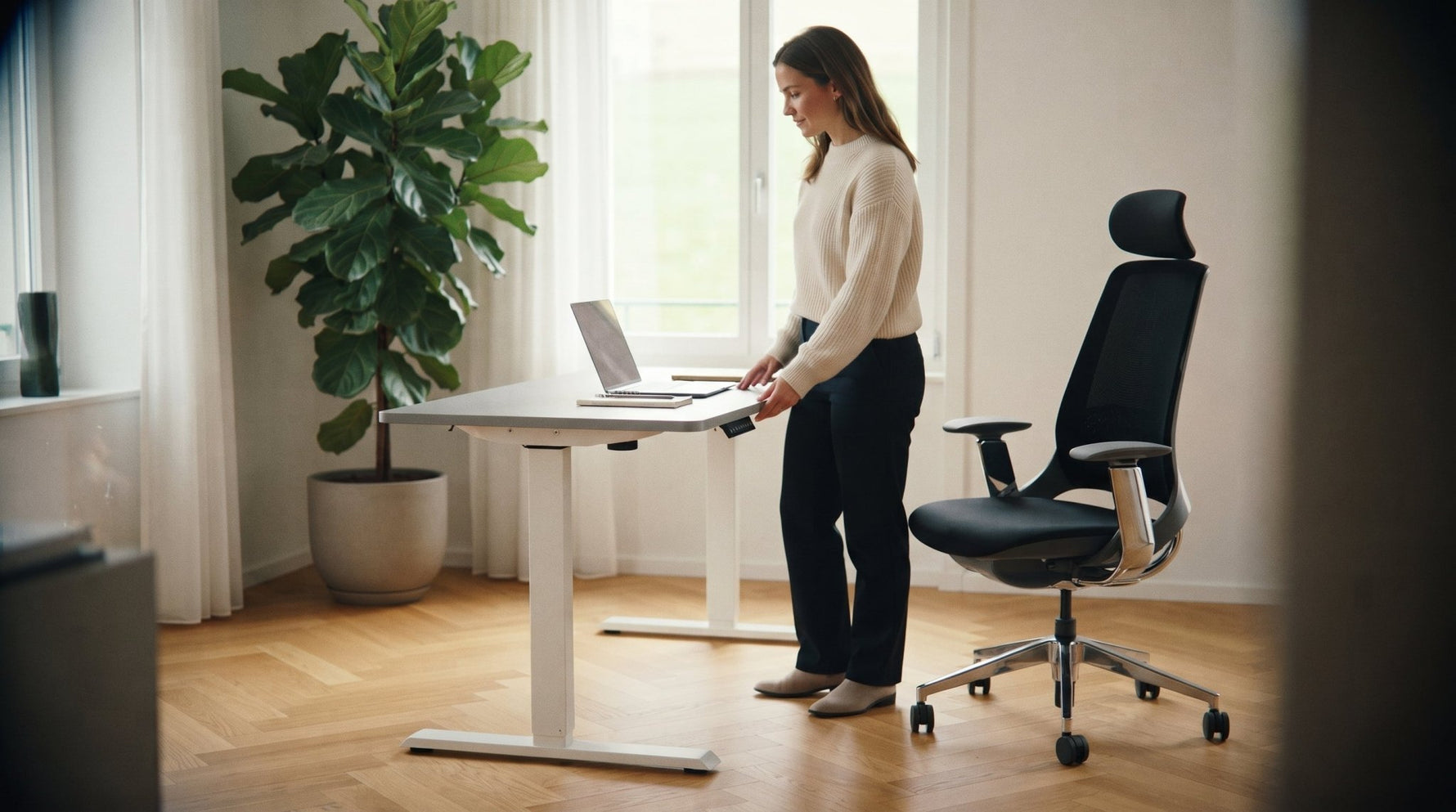 Frau stellt den TWHEELS Stehtisch per Bedienpanel auf Stehhöhe, Bürostuhl ProActive daneben