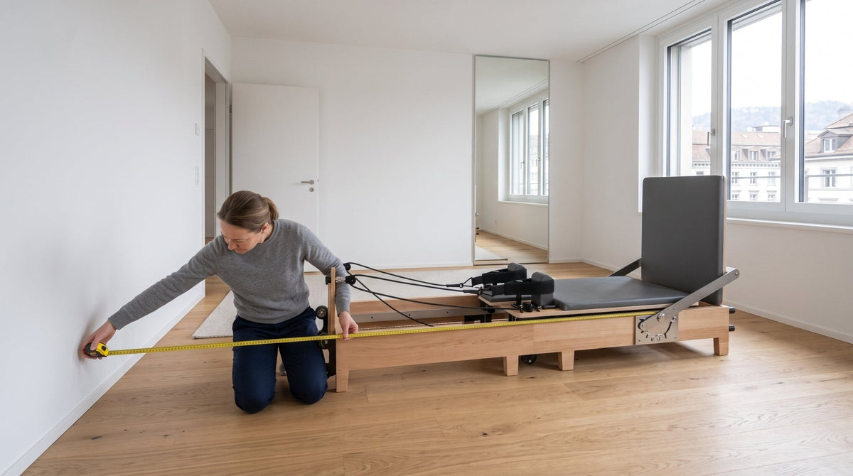 Frau kniet mit Massband vor einem Pilates Reformer aus Ahornholz und misst den Platzbedarf zur Wand im hellen Wohnraum