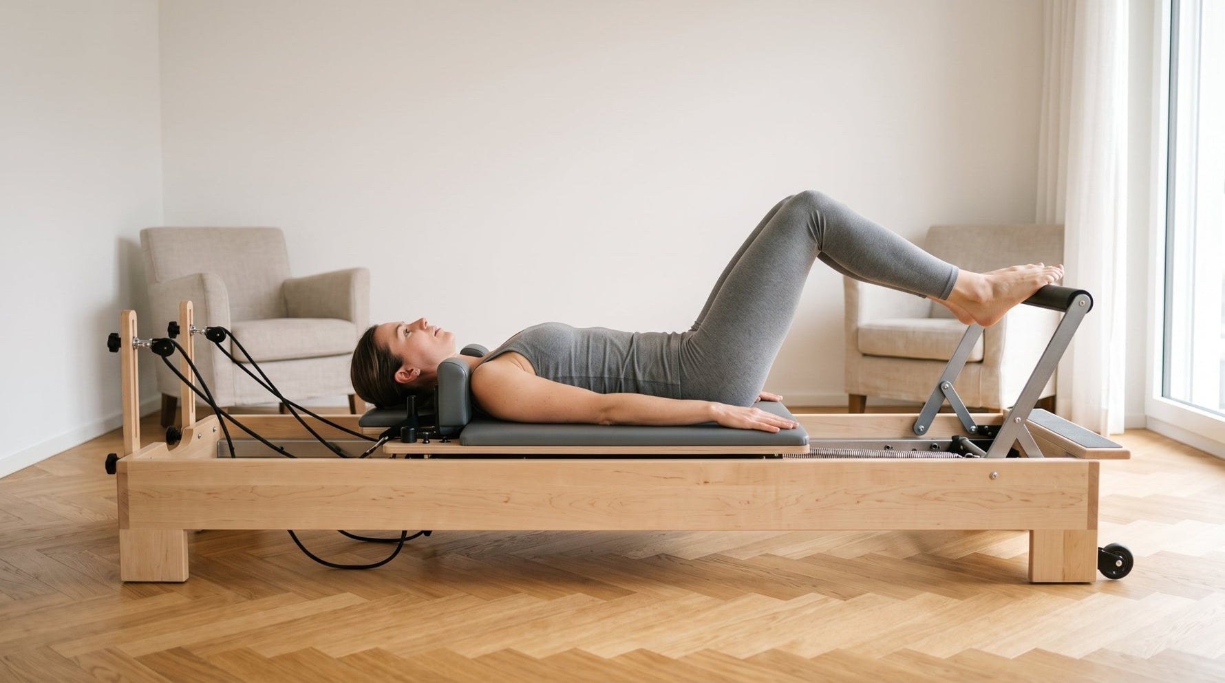 Frau trainiert Footwork auf dem TWHEELS Pilates Reformer aus Ahornholz, Wagen halb ausgefahren