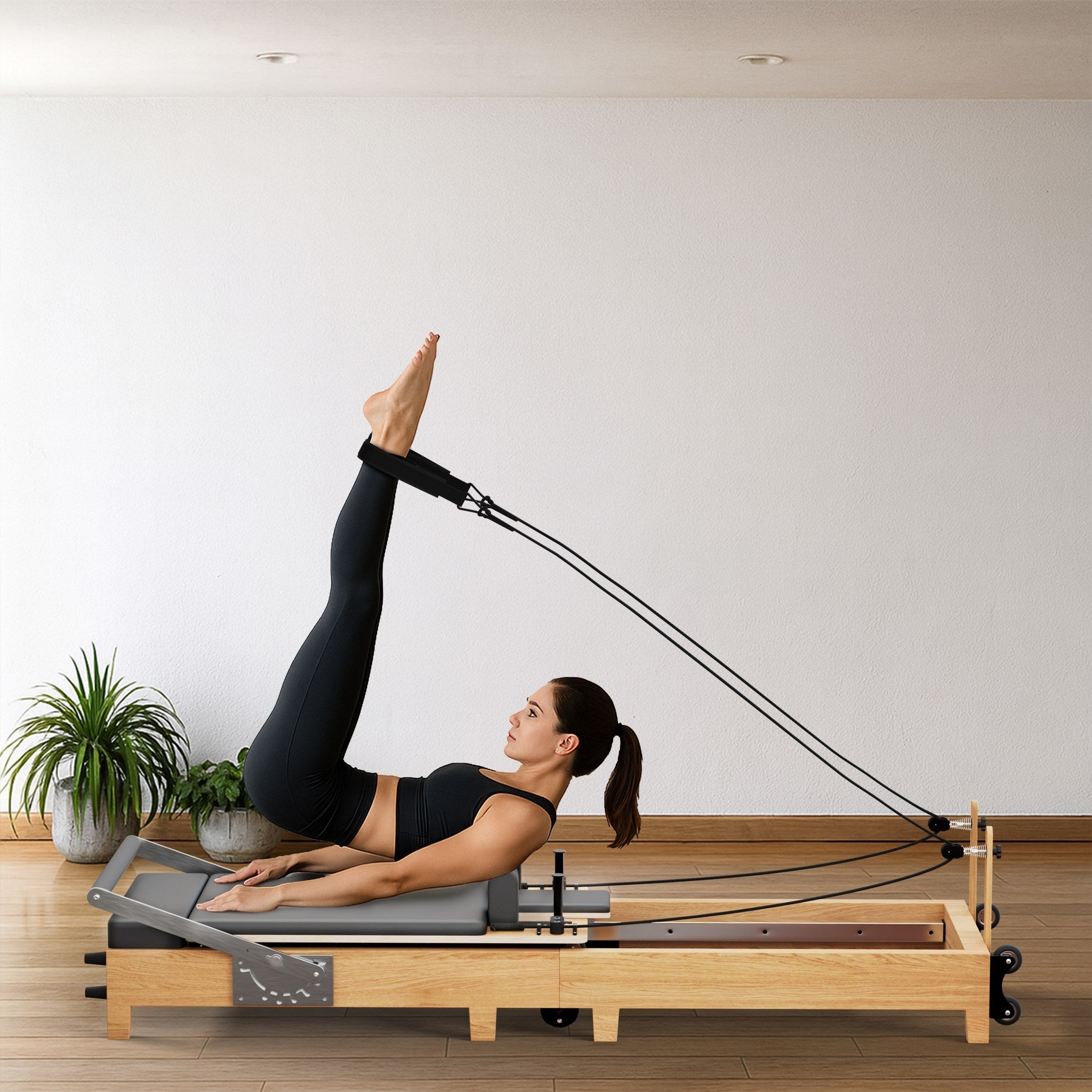 Frau trainiert am grauen TWHEELS Pilates Reformer aus Ahornholz im Home-Studio