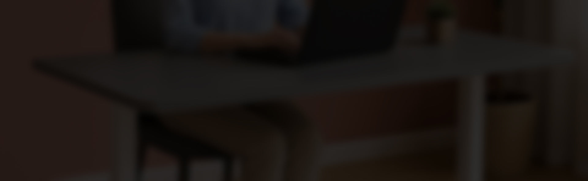 Person arbeitet an einem modernen Schreibtisch mit Laptop und Pflanze im Homeoffice.